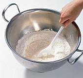 Mixing water with flour and yeast in bowl