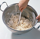 Mixing dough with spoon for preparation of pizza