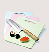 Messer und Sushi auf 3 bunten Küchen -brettchen