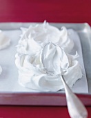 Spreading meringue on baking paper with spoon to raspberry pavlova