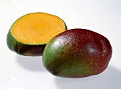Whole and halved reddish green mangoes on white background