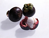 Two whole and one peeled mangosteen on white background