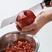 Close-up of hand's cutting pomegranate with knife