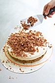 Close-up of chef spreading grated chocolate on walnut cake