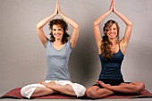 Portrait of two women sitting and performing yoga