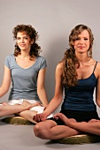 Two women sitting and performing yoga