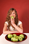 Sandra sitzt an Tisch vor Obst- schale mit Äpfeln