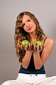 Frau sitzt Schneidersitz hat zwei Äpfel in der Hand