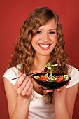 Frau hält Schale mit Salat und Gabel in der Hand