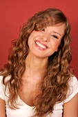 Beautiful woman with long curly hair wearing white top standing and laughing