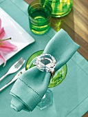 Turquoise napkin rolled in napkin ring with diamond