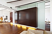 Giant brown cabinet in white room with high ceiling and sliding door