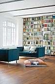 Sofas in Blau im Wohnraum in Weiß, Bücherregale, Sprossenfenster