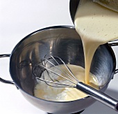 Close-up of liquid dough being poured in casserole with whisk