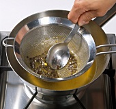 Hand filtering passion fruit liquid by sieve