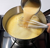 Close-up of creamy yolks being poured in passion fruit juice in pot