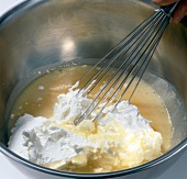 Close up of cream being whisked in pot while preparing maracuja mousse