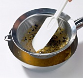 Seeds being squeezed with spatula through sieve