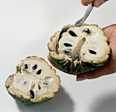 Close-up of hand removing pulp from custard apple