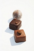 Square and round shaped chocolates with coffee bean on white background