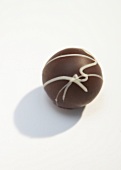 Round shaped chocolate candy with white stripes on white background