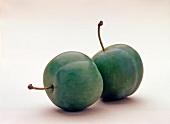 Two greengage plums on white background