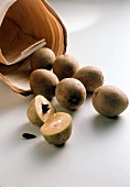 Halved and whole sapote on white background