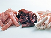 Close-up of various meat strips on white background