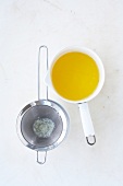 Melted butter in saucepan beside strainer