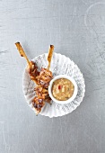Satay skewers with peanut sauce on paper plate