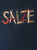 Salze written with colourful salt on black background