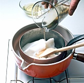 Sugar syrup being poured in pot for preparation of fondant, step 1