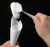Close-up of hand filling cream in piping bag, step 4