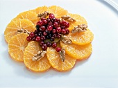 Oranges with cranberries and walnuts on white background