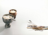 Wooden and silver vessels of steamed rice beside spoon, fork and chopsticks