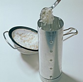 Rice being filled in container and soaked rice in sieve on white background, step 1