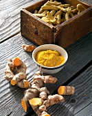 Turmeric powder in bowl with turmeric roots