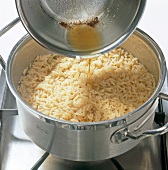 Close-up of melted butter being poured in long grain rice, step 4