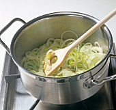 Onion leeks being sauteed with olive oil in casserole