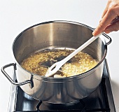 Reis, Zwiebeln, Butter im Kochtopf anschwitzen, Kochlöffel, Step 1