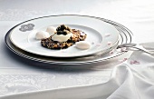 Fried wild rice with creme fraiche, caviar and flowers on plate