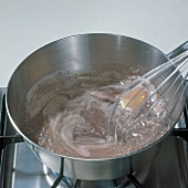 Butter sauce being stirred with whisk in saucepan