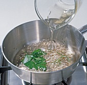 Close-up of white wine being poured on other ingredients in pan, step 2