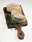 Buch vom Käse, 2 Hälften Bergkäse, rund, gewürzt, Holzbrett