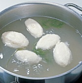 Close-up of dumplings and herbs being cooked in casserole, step 13