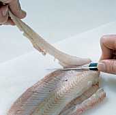 Close-up of hand cutting fillet of fish, step 8