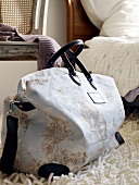 Close-up of white weekender bag with toile de jouy pattern and leather handles