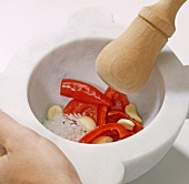 Close-up of peppers, paprika, garlic and salt in mortar with pestle, step 2