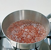 Close-up of boiling shallots and red wine in sauce pan, step 2