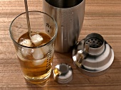 Close-up of whiskey with ice cubes besides shaker